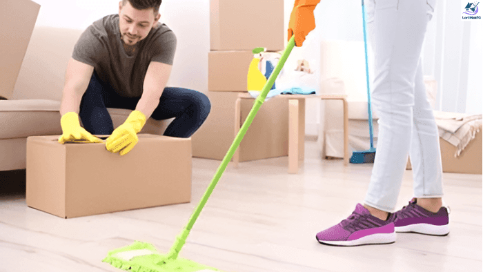 A person mopping the floor while other is opening a card board box to unpack house stuff.