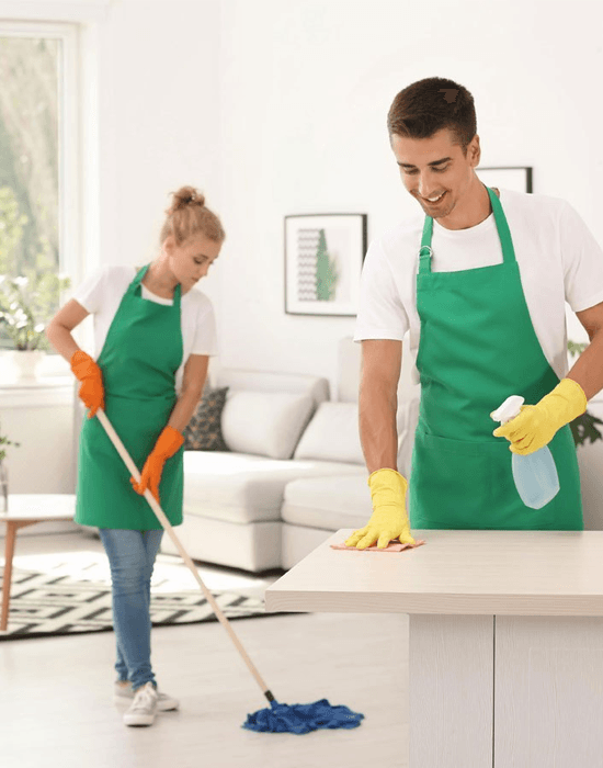 Professional house cleaners mopping floor and wiping counter top.