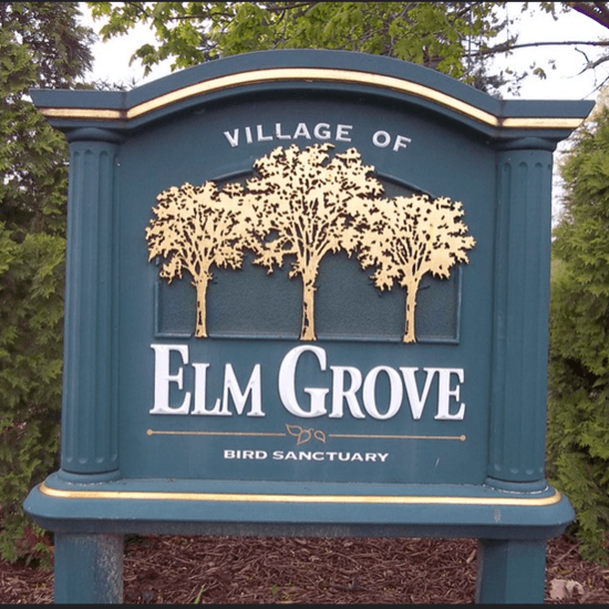 A sign board saying village of Elm Grove.